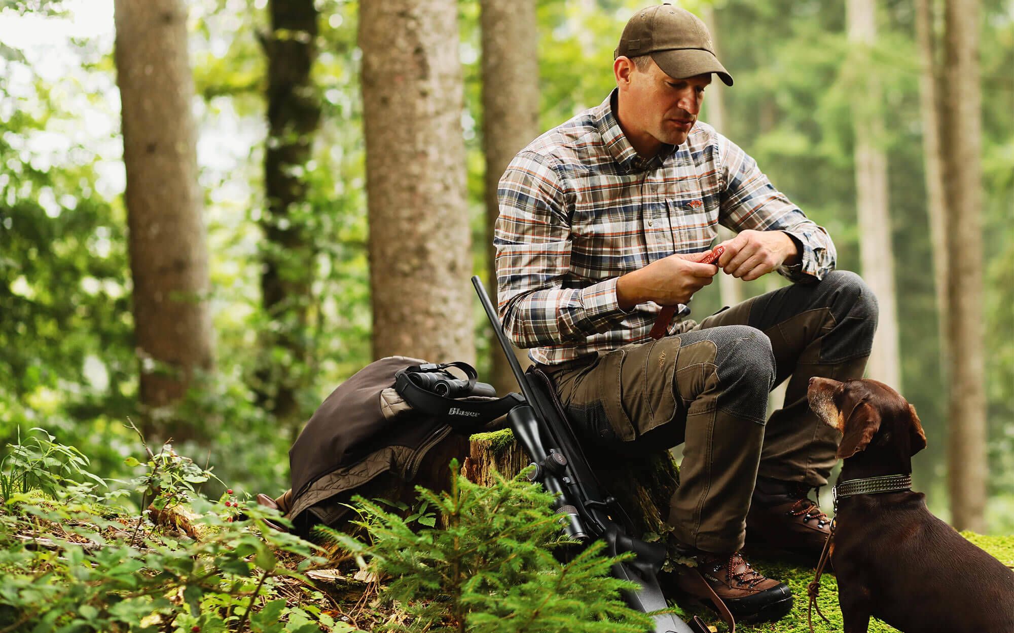 Ein Bild bei demein Mann  "Jäger" mit seinem Hunf im Wald sitzt